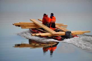 Mannen met rubberboot vervoeren hout