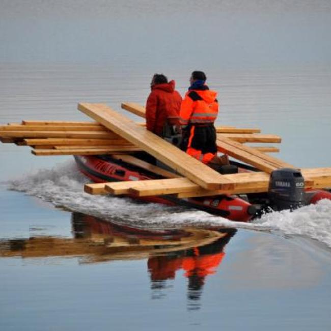Mannen met rubberboot vervoeren hout