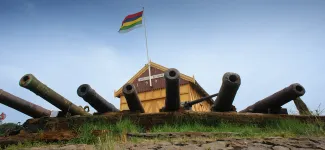 Clubhuis duikteam Ecuador met oude scheepskanonnen en Terschellinger vlag.